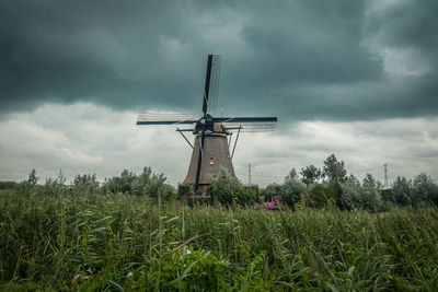 Traditional windmill on field against cloudy sky