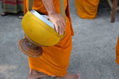 Low section of monk with bag standing on street