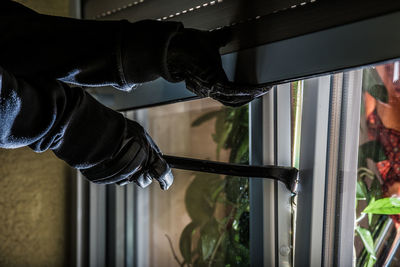 Cropped hands of burglar opening window