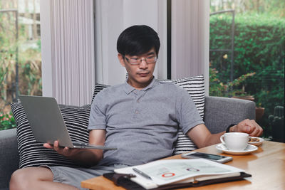 Midsection of man using mobile phone while sitting on table