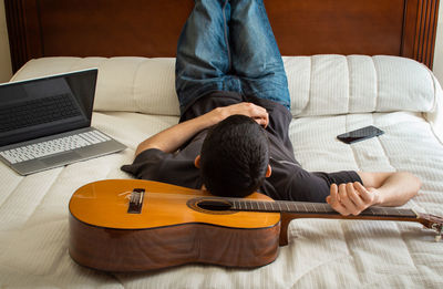 Rear view of man using mobile phone on sofa