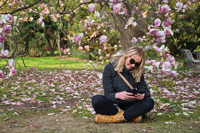 Woman using mobile phone while sitting in park