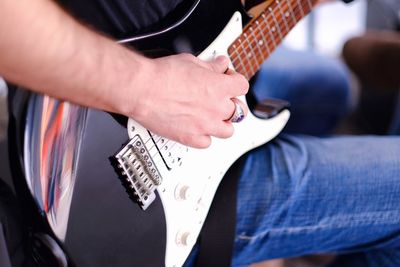 Midsection of man playing guitar