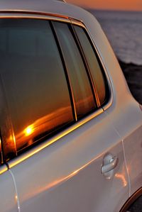 Close-up of side-view mirror at sunset