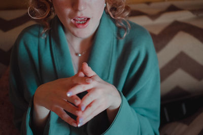 Midsection of young woman sitting against wall at home