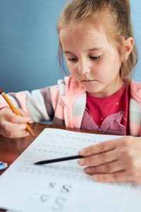 Little girl preschooler learning to write letters with help of her tutor. kid writing letters