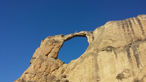 Low angle view of rock formation against clear blue sky