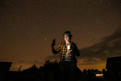 Side view of woman standing against sky at night