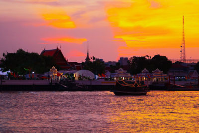 Sailboats moored in river against sky during sunset