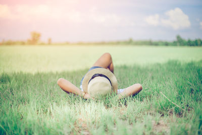 Carefree woman with hands behind head lying on grassy field