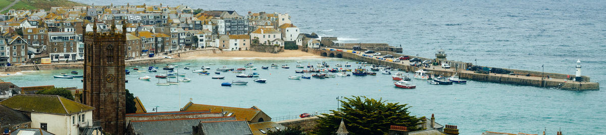 Panoramic view of boats moored by city on sea