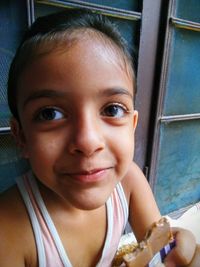 Close-up of girl eating chocolate against window