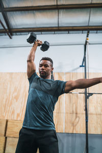 Man lifting dumbbell against wall