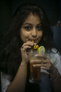 Close-up portrait of a young woman drinking glass