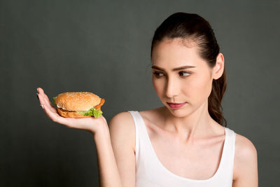 Woman holding burger against gray background