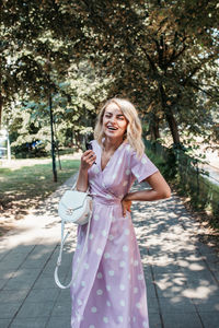 Cheerful woman standing on footpath