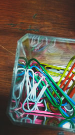 Close-up of multi colored paper clips in container at table