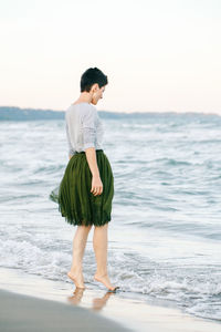 Full length of woman standing on shore at beach