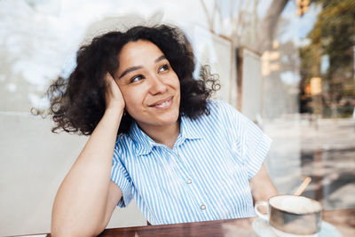 Smiling woman with coffee cup sitting at table in cafe