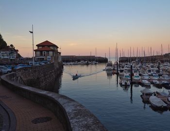 Boats moored at harbor against sky during sunset