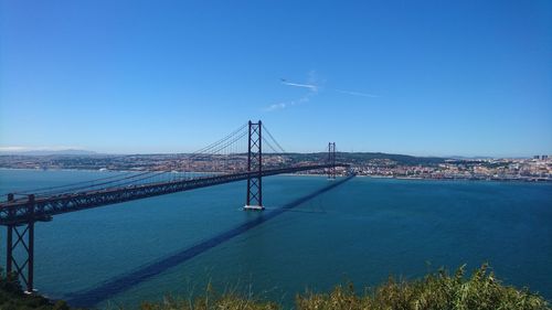 Suspension bridge over river against blue sky