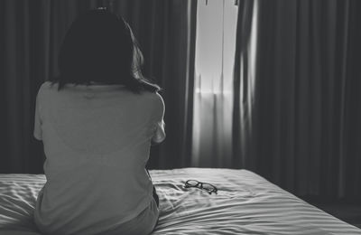 Rear view of shirtless boy sleeping on bed at home