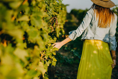 Midsection of woman standing by plants on field