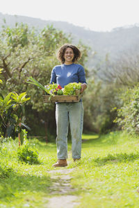 Full length portrait of a smiling woman standing in farm