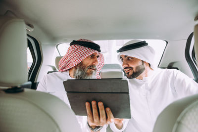 Business people discussing over digital tablet while sitting in car
