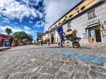 People walking on street in city against sky