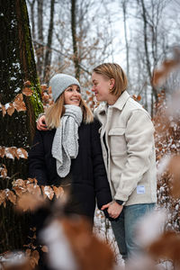 Portrait of smiling couple standing in winter forest
