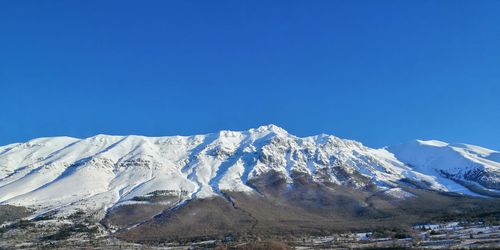 Snowcapped mountains against clear blue sky