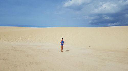 Full length of woman standing on sand at desert against sky