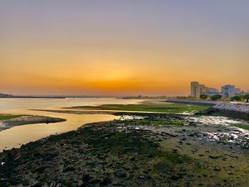 Scenic view of sea and buildings against sky during sunset