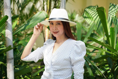 Portrait of young woman standing against plants