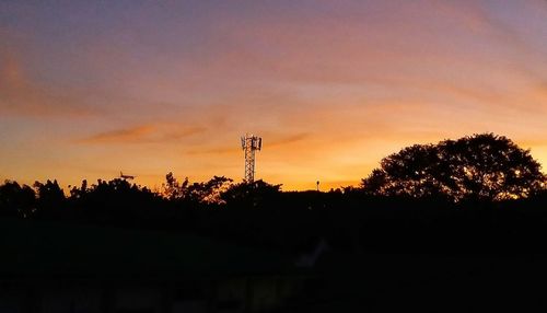 Silhouette trees on field against sky during sunset