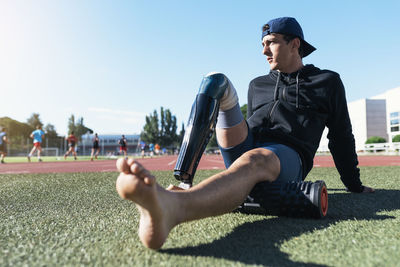 Young athlete with prosthetic leg relaxing at sports track