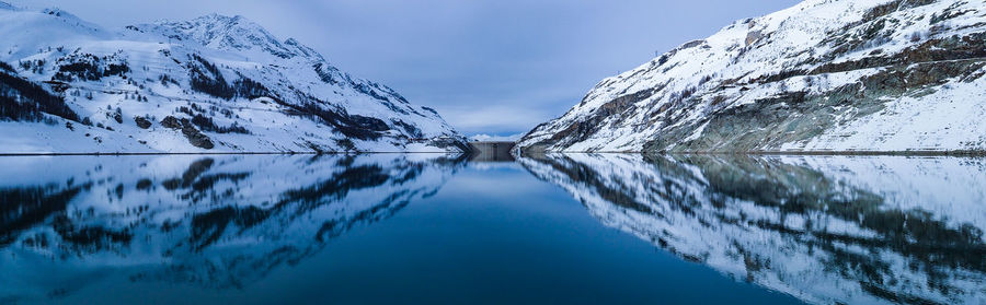 Scenic view of lake by snowcapped mountain against sky
