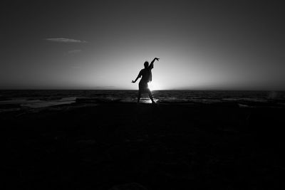 Silhouette of woman jumping on beach