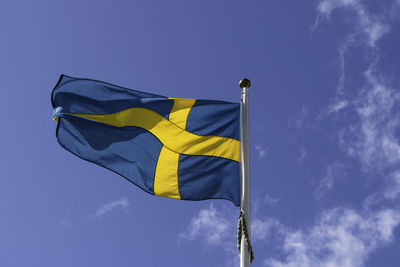 Low angle view of flag against blue sky