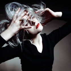 Beautiful young woman with hand in hair looking away in darkroom