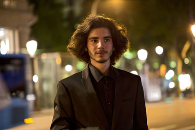 Portrait of young man in illuminated city at night