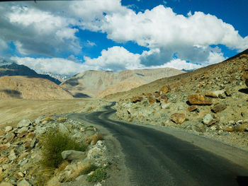 Scenic view of road by mountains against sky