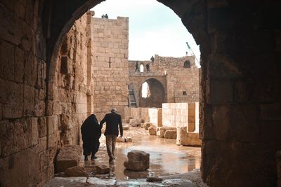 Traditional muslim couple under the arch of an old historal sea castle