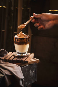 Cropped hand of person pouring drink on table