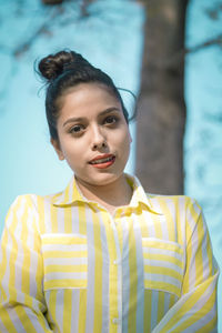 Portrait of young woman standing against yellow water