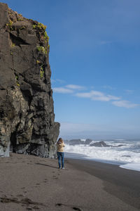 Rear view of woman at beach against sky