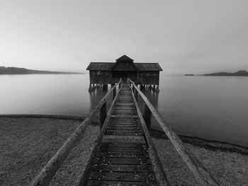 Pier and boat house over lake against clear sky
