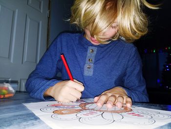 Close-up of boy drawing on paper at table in home