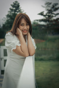 Portrait of young woman standing against trees